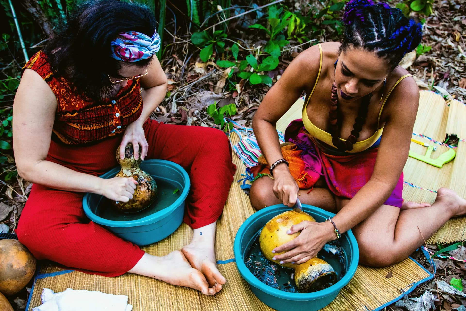 Duas artesãs sentadas no chão, lavando as cabaças em bacias azuis